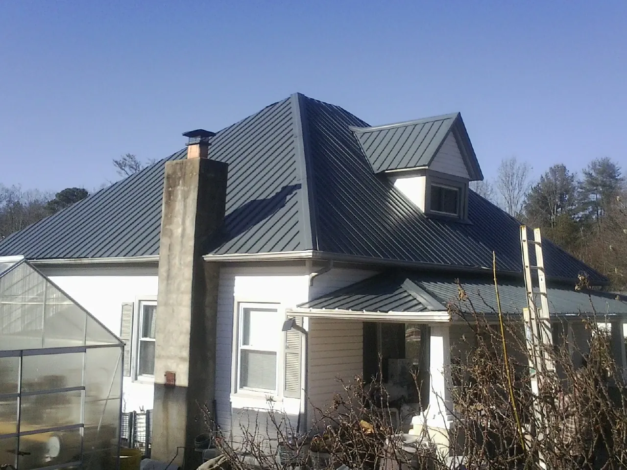 Dark blue standing seam metal roof on a white farmhouse with dormer — Slate & Tile Roof Repair by Roofing Brothers in Hatboro