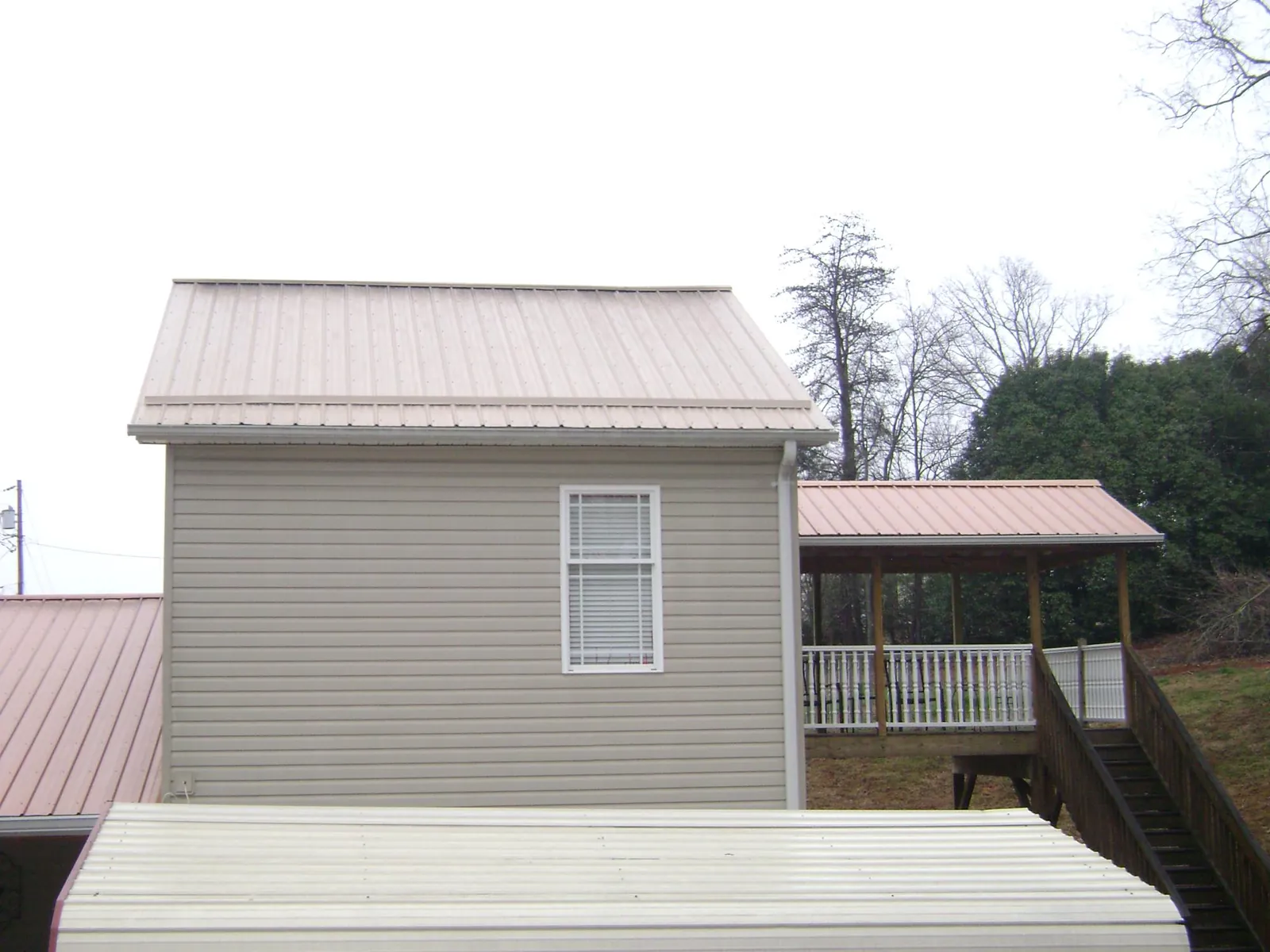 Tan metal roofs on a two story addition and attached porch, from a Roof Replacement job in Hatboro