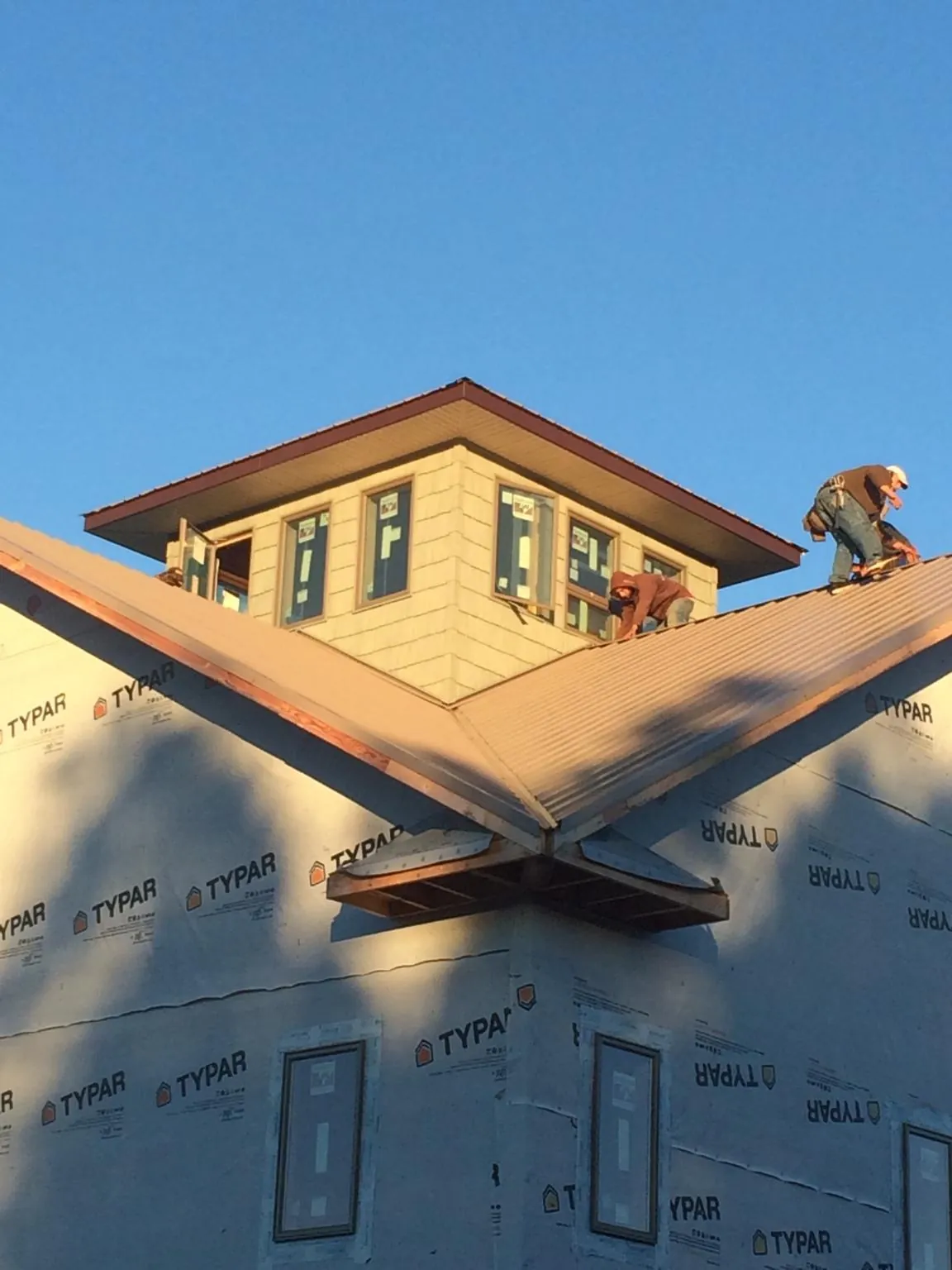 Roofers working around a rooftop cupola on a new metal roof at sunset — Roof Waterproofing in Hatboro by Roofing Brothers